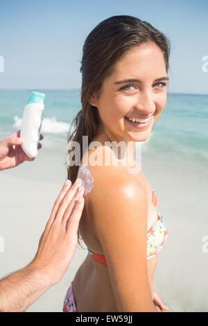 Man putting sun tan lotion on his girlfriend Stock Photo