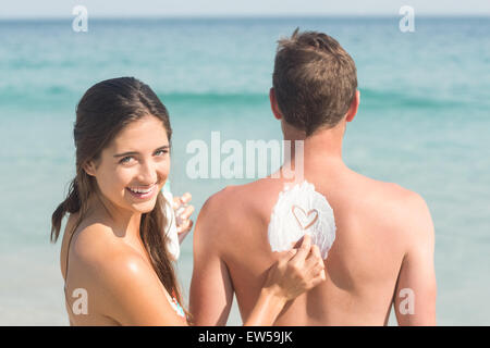 Woman putting sun tan lotion on her boyfriend Stock Photo