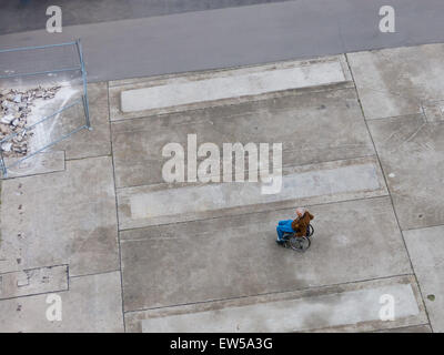 Lonely Senior in wheelchair on a big gray area, viewed from above. Stock Photo