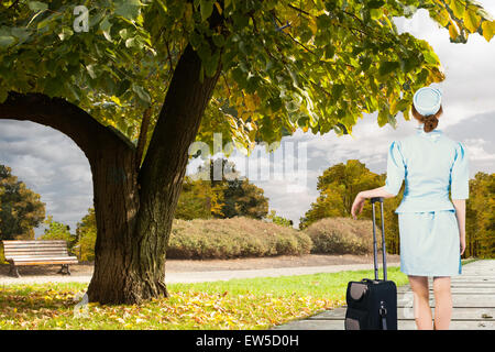 Composite image of pretty air hostess leaning on suitcase Stock Photo