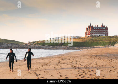 Two surfers walking along Fistral Beach in Newquay in Cornwall. UK. Stock Photo