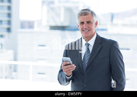 Smiling businessman using his smartphone Stock Photo