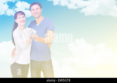 Composite image of couple holding fan of cash Stock Photo