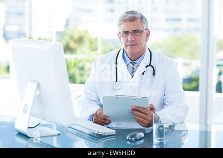 Smiling doctor working on computer at his desk Stock Photo