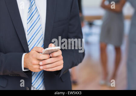 Businessman texting with colleagues behind him Stock Photo