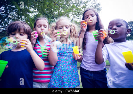 Children playing with bubble wand in the park Stock Photo