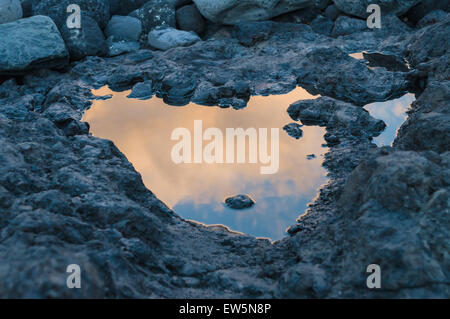 Sunset reflection in small puddle on volcanic ground Stock Photo