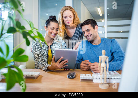 Smiling business team working together with tablet Stock Photo