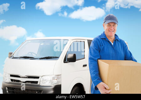 Composite image of happy delivery man holding cardboard box Stock Photo