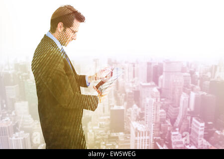 Composite image of businessman standing while using a tablet pc Stock Photo