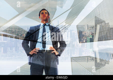 Composite image of serious businessman with hands on hips Stock Photo