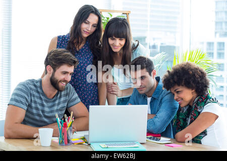 Happy creative business team gathered around a laptop Stock Photo