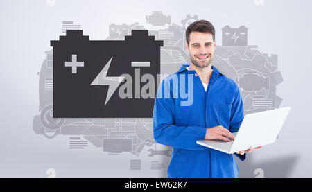 Composite image of happy young male mechanic using laptop Stock Photo