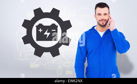 Composite image of smiling male mechanic using his mobile phone Stock Photo