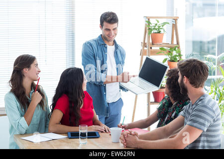 Young businessman showing his laptop to colleagues Stock Photo