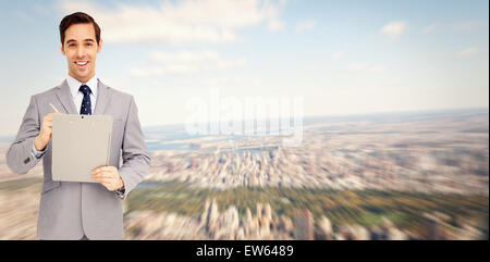 Composite image of happy businessman holding a clipboard Stock Photo