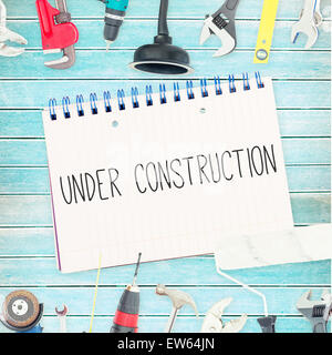 Under construction against tools and notepad on wooden background Stock Photo