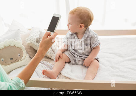 Happy mother using her phone with her baby boy Stock Photo