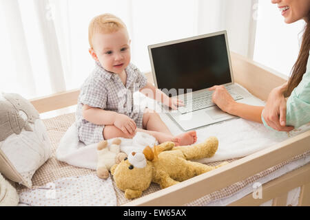 Happy mother using laptop with her baby boy Stock Photo