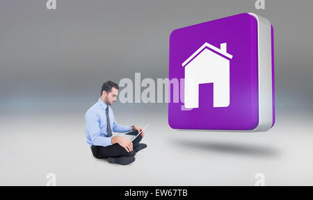 Composite image of cheerful businessman sitting on the floor using laptop Stock Photo