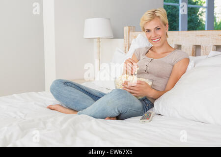 Portrait smiling blonde woman eating pop corn Stock Photo