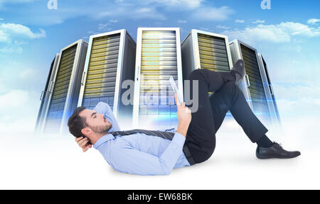 Composite image of businessman lying on floor using tablet Stock Photo