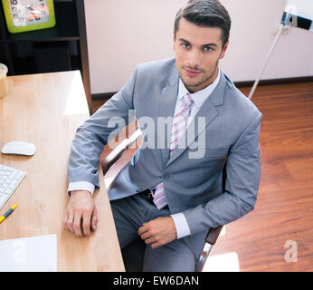 Handsome businessman sitting at the table in office and looking at camera Stock Photo