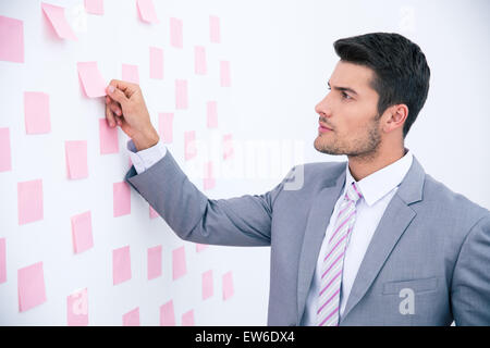 Handsome businessman looking on sticker at wall in office Stock Photo