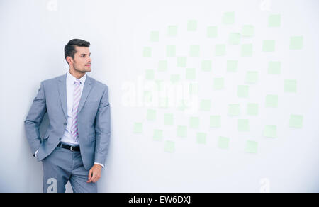 Businessman leaning on the wall and looking on stickers Stock Photo