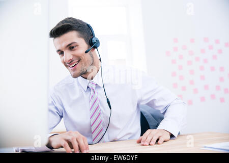 Portrait of a smiling male operator with headset sitting at the table in office Stock Photo