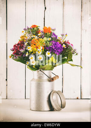 Summer flower bouquet in old milk canister in front of rustic wooden wall, vintage processing Stock Photo