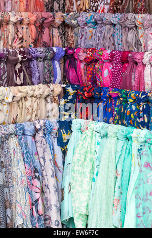 Colourful scarves for sale on market stall in Dorchester, Dorset, UK in June - hanging tied with knots Stock Photo