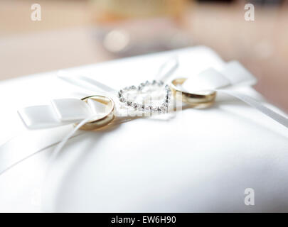 on a white velvet cushion are two rings decorated with a heart of diamonds Stock Photo