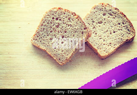 Retro vintage toned two slices of wholewheat bread and a knife on bamboo table. Stock Photo