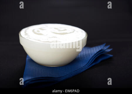 Bowl of fresh garlic dip sauce on blue napkin with black background Stock Photo