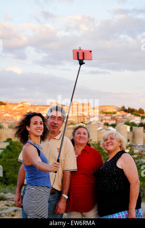 Tourists taking selfie photos next to Cuatro Postes (Four Posts) viewpoint overlooking medieval town of Avila, Spain Stock Photo
