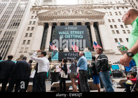 New York, USA. 18th June, 2015. People line up for free t-shirts outside the New York Stock Exchange decorated for the Fitbit initial public offering on Thursday, June 18, 2015. So far shares have surged from $20 to $30.40 raising $732 million. The fitness tracking device company created a carnival atmosphere surrounding their IPO with an exercise class and free t-shirts . Credit:  Richard Levine/Alamy Live News Stock Photo