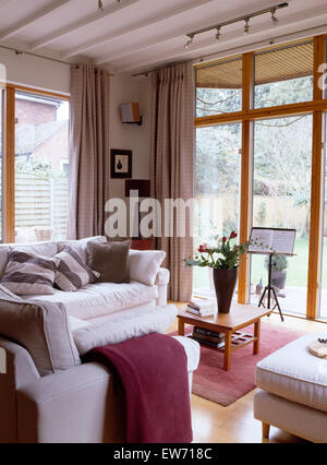 White sofas in modern living room extension with glass doors to the garden Stock Photo