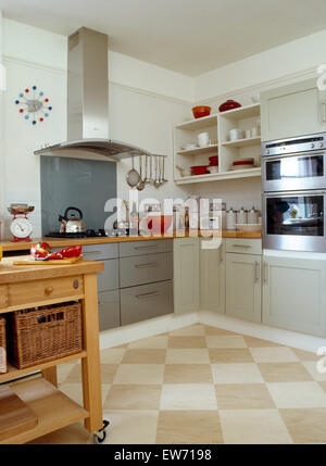 Checkerboard tiled flooring in modern kitchen with stainless steel extractor above hob in gray fitted unit Stock Photo