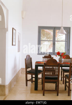 Fretwork backs on chairs at simple table in modern white Moroccan dining room with marble flooring Stock Photo