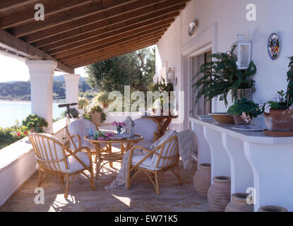 White cushions on cane chairs on shady veranda of house on the island of Corfu with a view of the sea Stock Photo