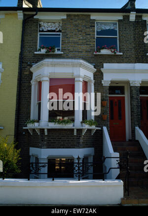 Exterior of Victorian terraced townhouse with red blind behind bay window Stock Photo