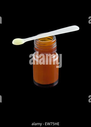 Royal Jelly cream spoonful, and contents, an alternative  raw medication made by Apis genus honeybees. Isolated black background Stock Photo