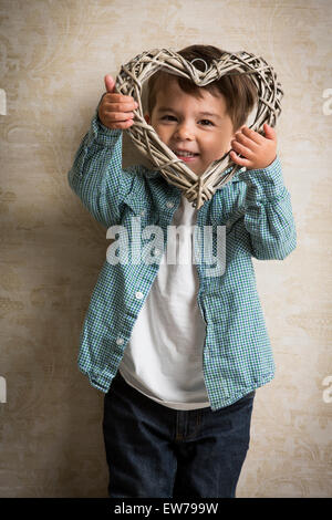 Little boy holding a wooden heart in his hand Stock Photo