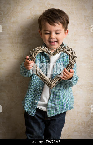 Little boy holding a wooden heart in his hand Stock Photo