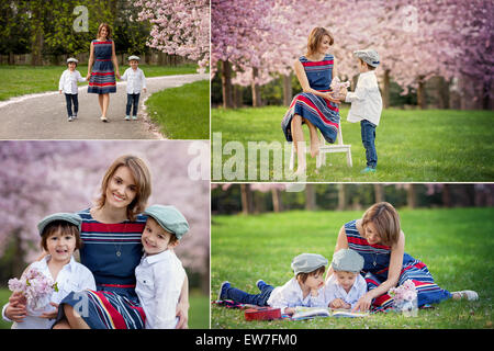 Beautiful portrait of mother and her two children in a cherry blossom tree garden, waking down the alley, holding hands and look Stock Photo