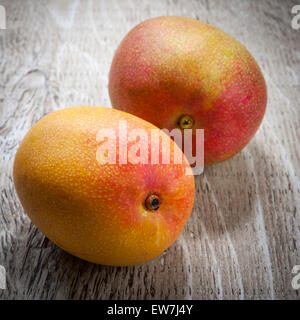 Two ripe whole mango fruits on rustic wood background Stock Photo
