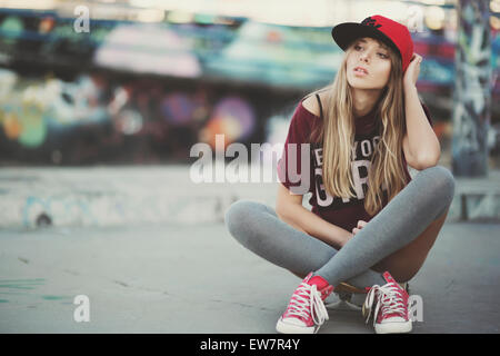 Young woman sitting on a skateboard, Seville, Spain Stock Photo