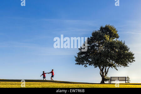 Two girls playing by a tree, Cottesloe, Perth, Australia Stock Photo