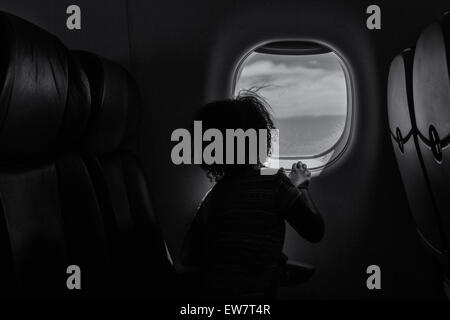 Rear view of a girl looking out of the window on a plane Stock Photo
